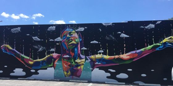 A rainbow figure stretches out their arms in a St Pete mural
