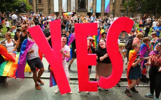 MELBOURNE, AUSTRALIA - NOVEMBER 15: People in the crowd celebrate as the result is announced during the Official Melbourne Postal Survey Result Announcement at the State Library of Victoria on November 15, 2017 in Melbourne, Australia. Australians have voted for marriage laws to be changed to allow same-sex marriage, with the Yes vote defeating No. Despite the Yes victory, the outcome of Australian Marriage Law Postal Survey is not binding, and the process to change current laws will move to the Australian Parliament in Canberra. (Photo by Scott Barbour/Getty Images)