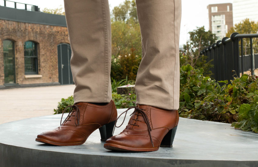 Man standing on platform in park wearing high heels