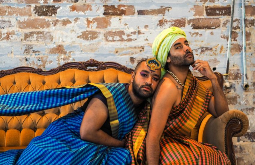 Two men sit on lounge waering saris