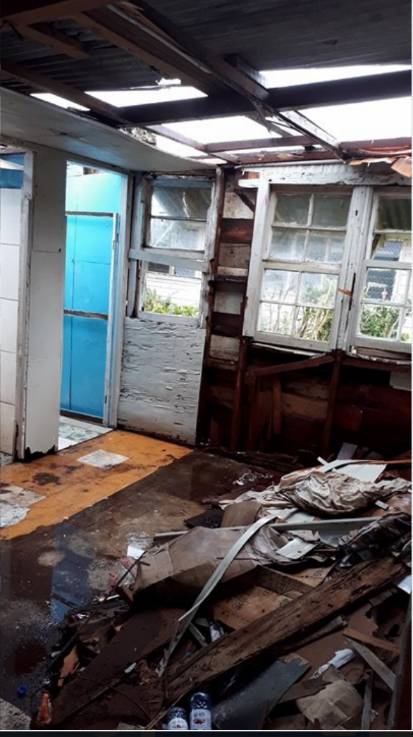 Inside of a wooden building with broken doors and debris everywhere