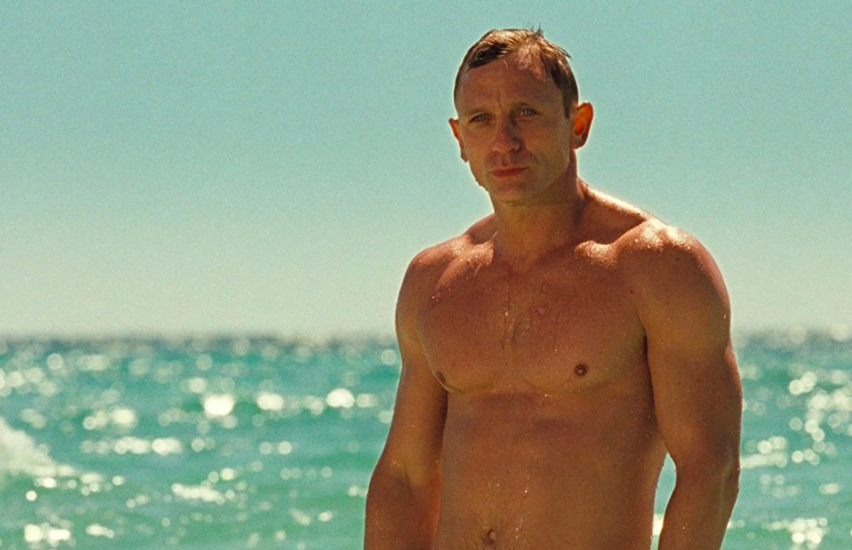 Daniel Craig walks out of the sea.
