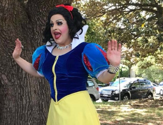 Drag queen hannah conda dressed as snow white standing in a park with her hands up