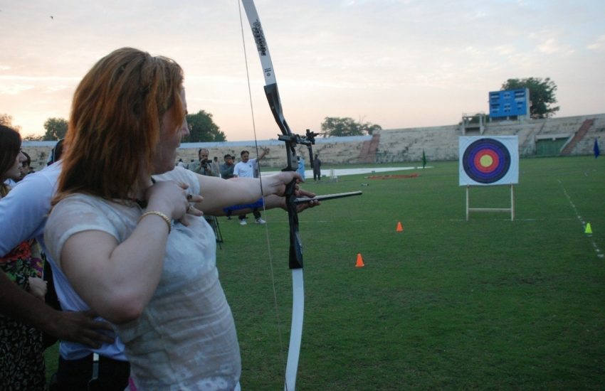 Woman drawing a bow and arrow pointed at an archery target