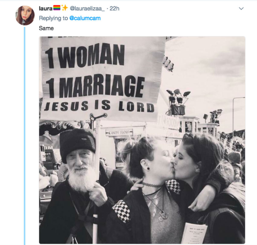 A screenshot of two women kissing in front of Christian protester