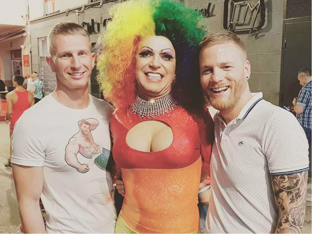 Two men posing with a drag performer
