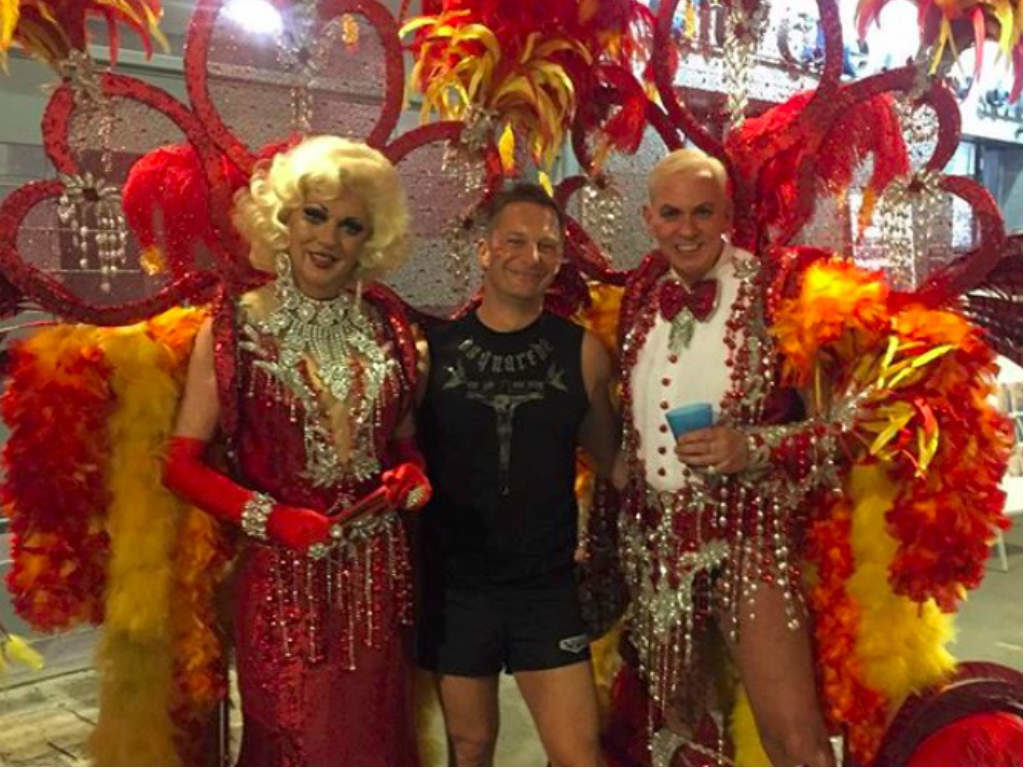Two performers posing for a picture with a man at Sitges Pride