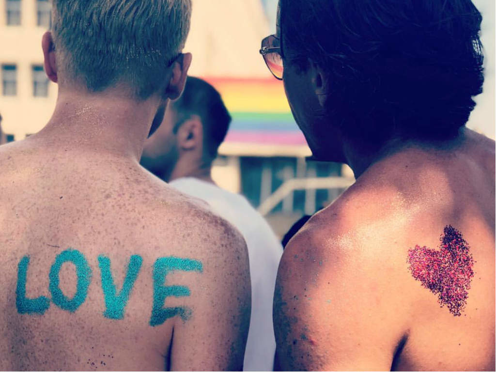 Two men's backs with the word 'love' and a heart made of glitter