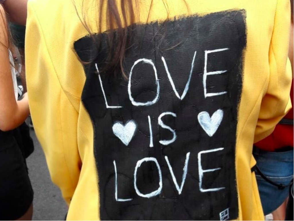 A girl wearing a yellow jacket with a 'love is love' writing on the back