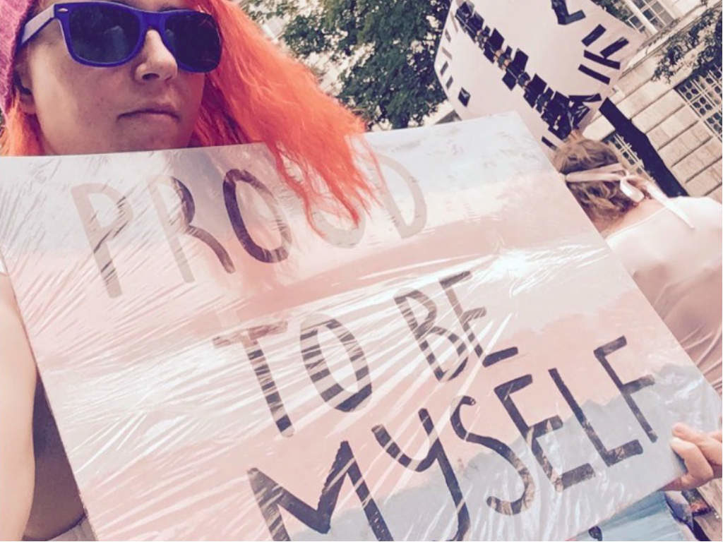 A girl holding a 'proud to be myself' sign