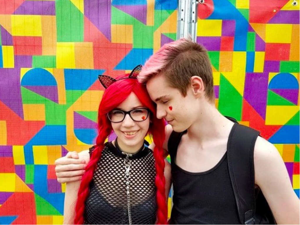 Two friends hugging against a multicolored background