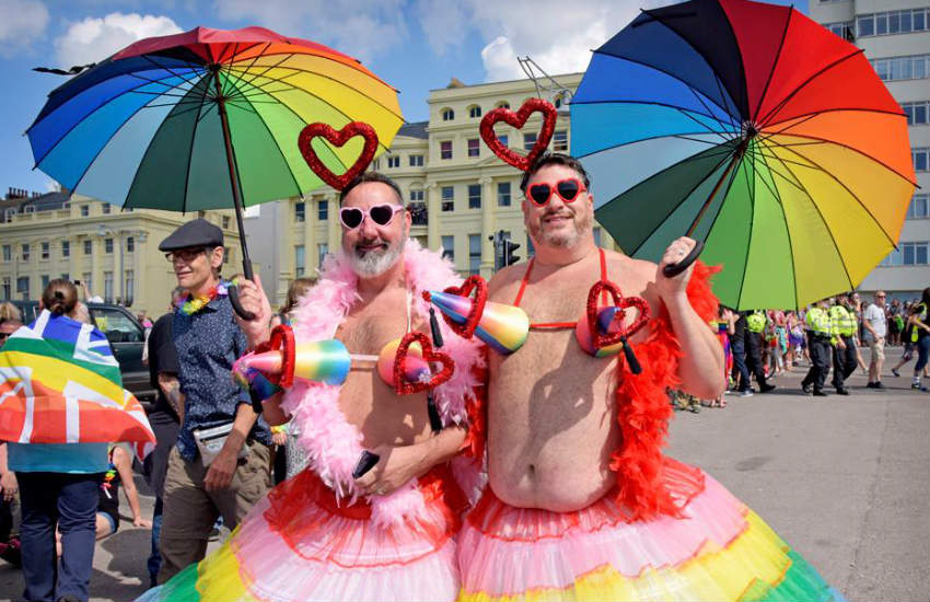 Two marchers sporting rainbow outfits and umbrellas at Brighton Pride in 2017.