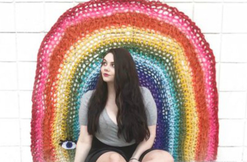 NeonFiona sitting in front of crocheted rainbow