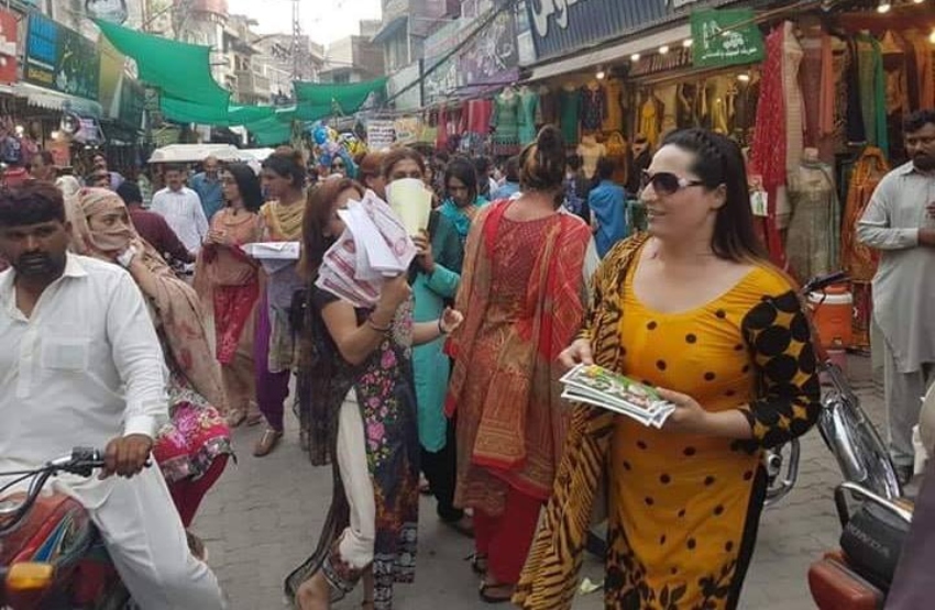 trans women handing out leaflets in a colourful pakistani market street