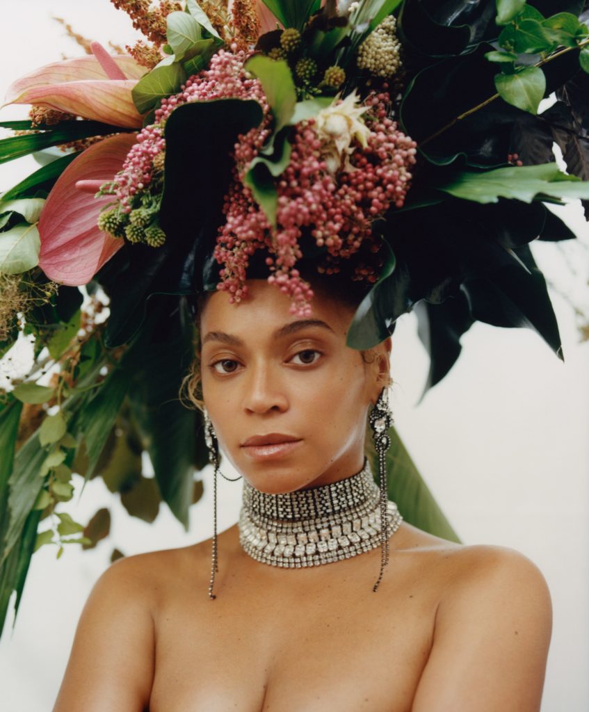 head shot of an apparently topless beyonce who is wearing a silver choker and a very elaborate floral head piece