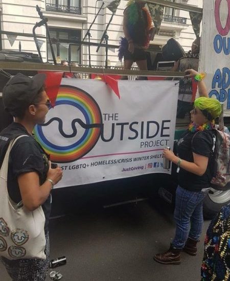 two people looking at a banner outside that reads the outside project