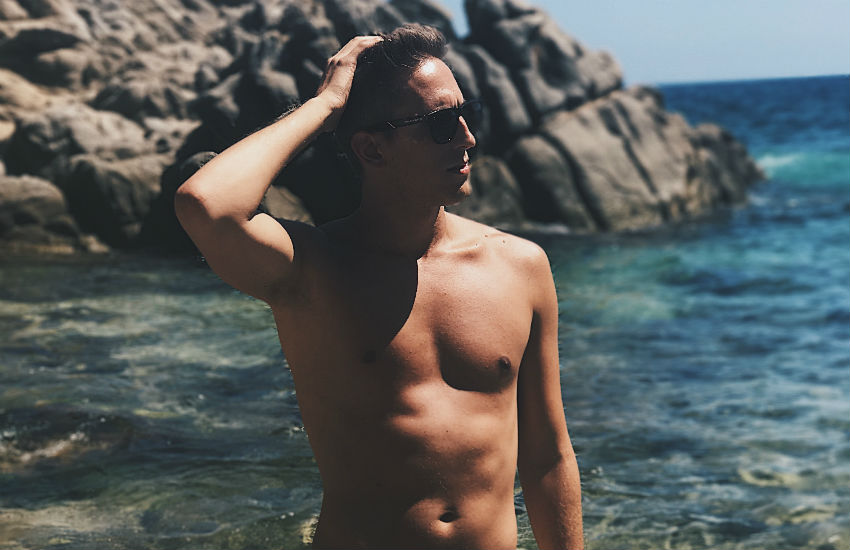 Roi Sastre on a beach shirtless in his speedos