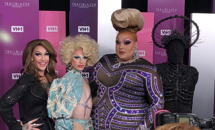 four drag queens posing on the red carpet.