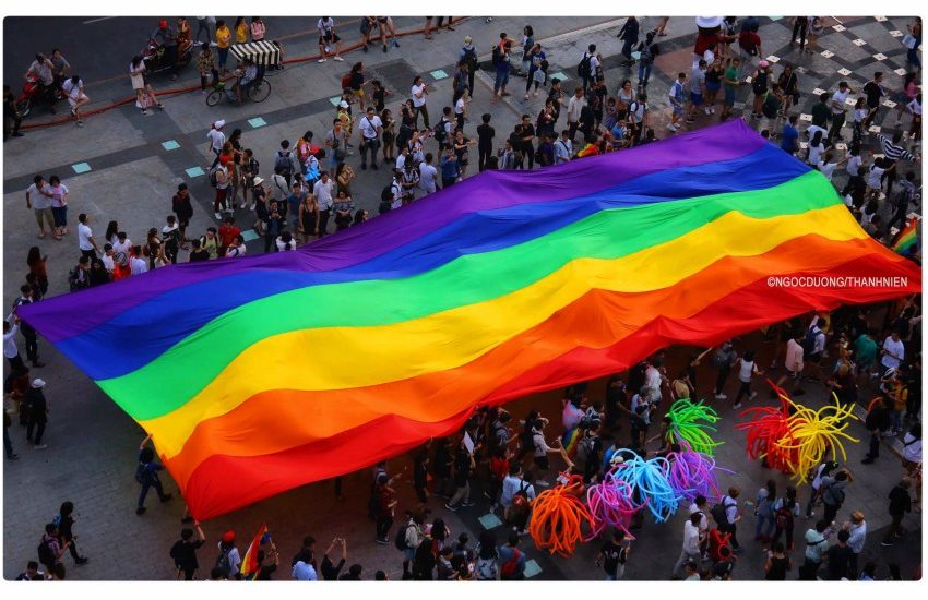 a giant rainbow flag is dragged along the street