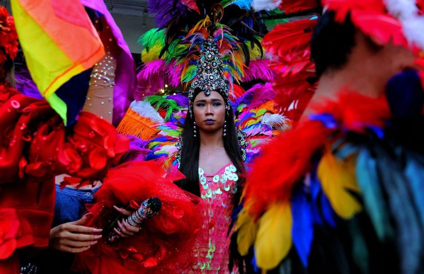 a drag queen in an elaborate carnival costume with a big headpiece and feathers