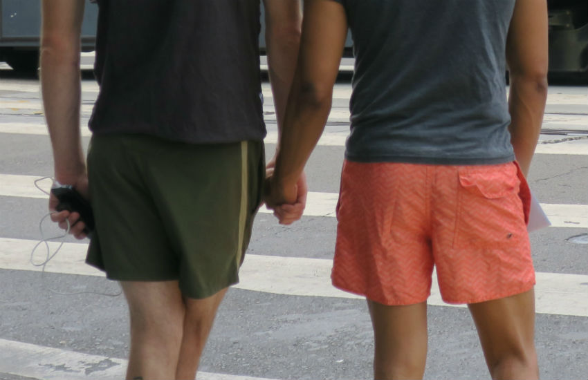 Two men holding hands at the street light