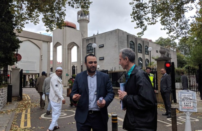 two men standing outside a huge mosque talking to each other