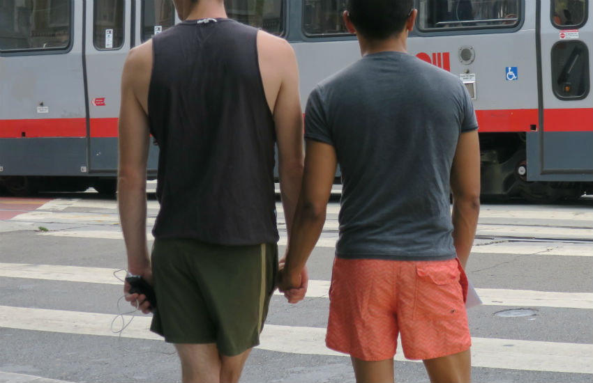 Two men holding hands at a street light