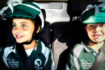 Millie and Poppy Bell sit in their riding outfits in the back seat of a car.