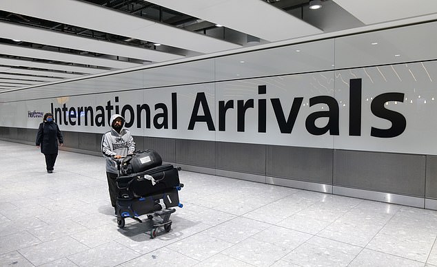 A man is pictured pushing his luggage at Heathrow airport in west London on Wednesday