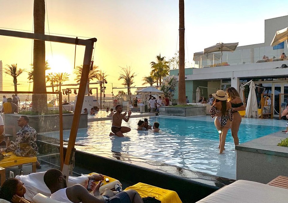 Instagram influencers pose in a swimming pool in Dubai today as other Britons rushed to get home before the 1pm deadline